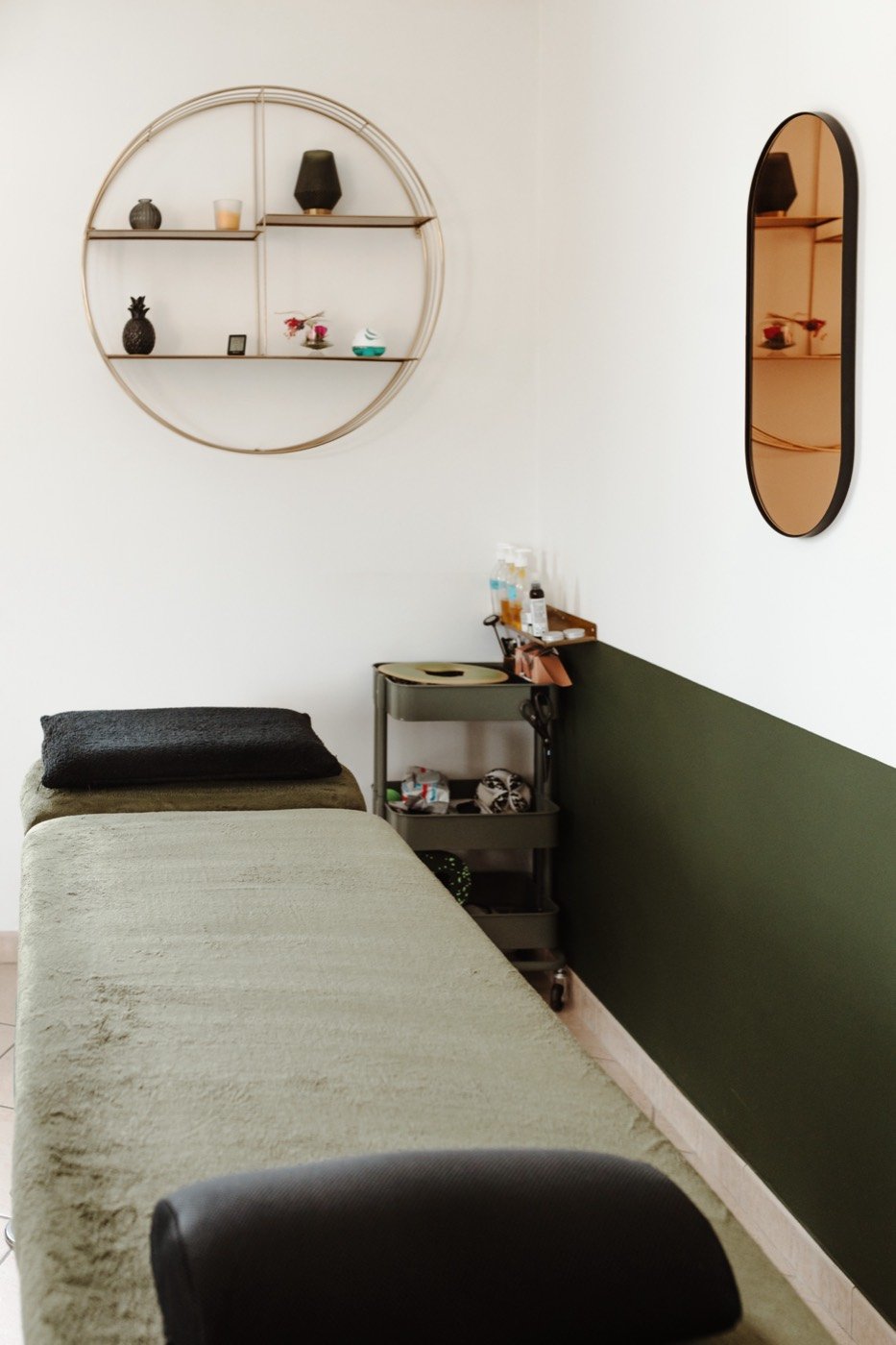 Table de soin du cabinet d'ostéopathie, mur vert sapin et étagère ronde en laiton