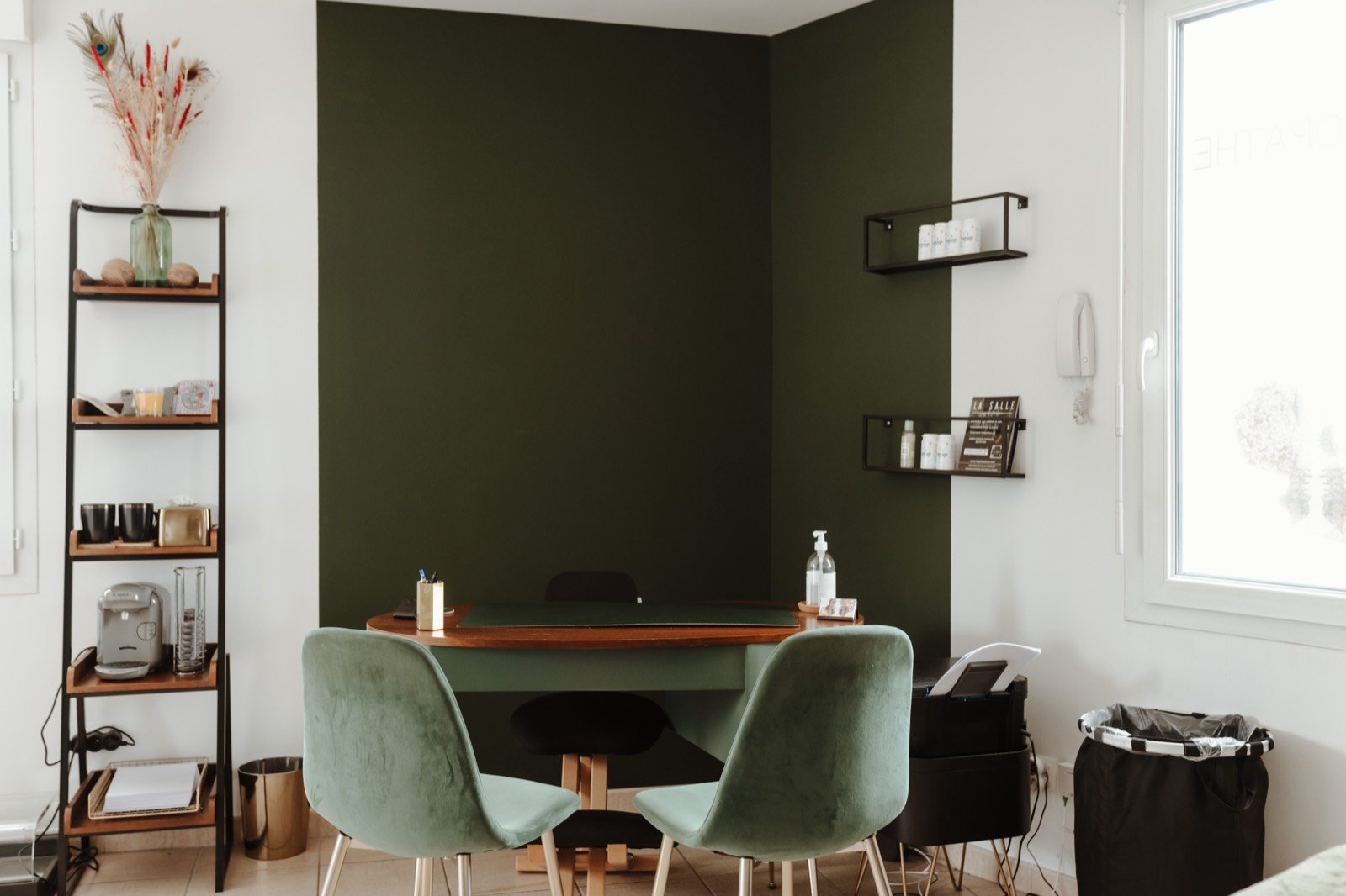 Bureau de consultation du cabinet d'ostéopathie de Grégory Dabriou : mur vert sapin, bureau en bois et chaises en velours vert